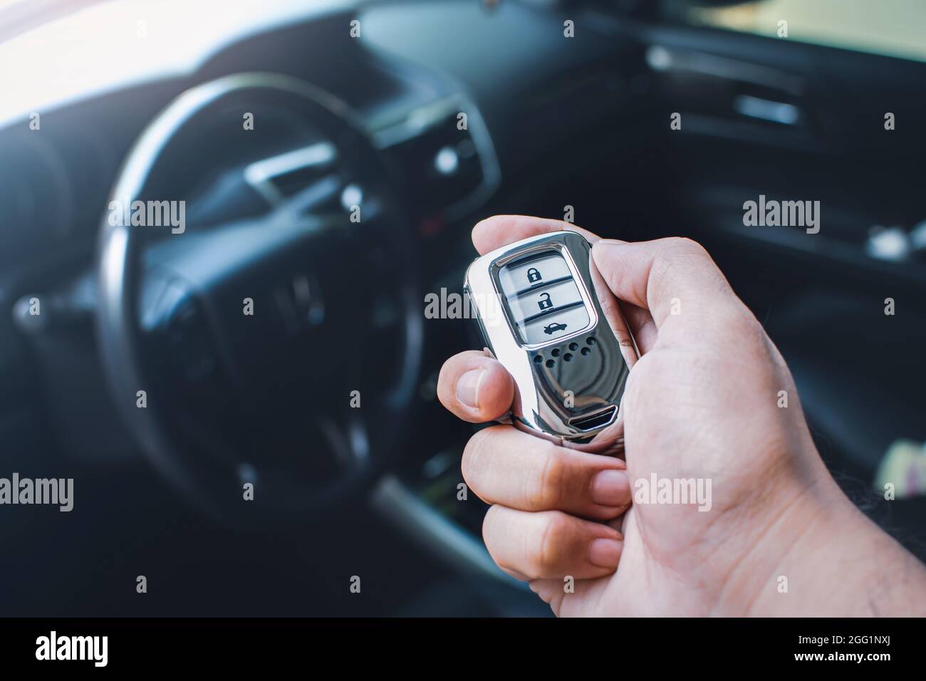 Car keyless entry remote in a hand of the owner car with car interior blurred background Stock Photo