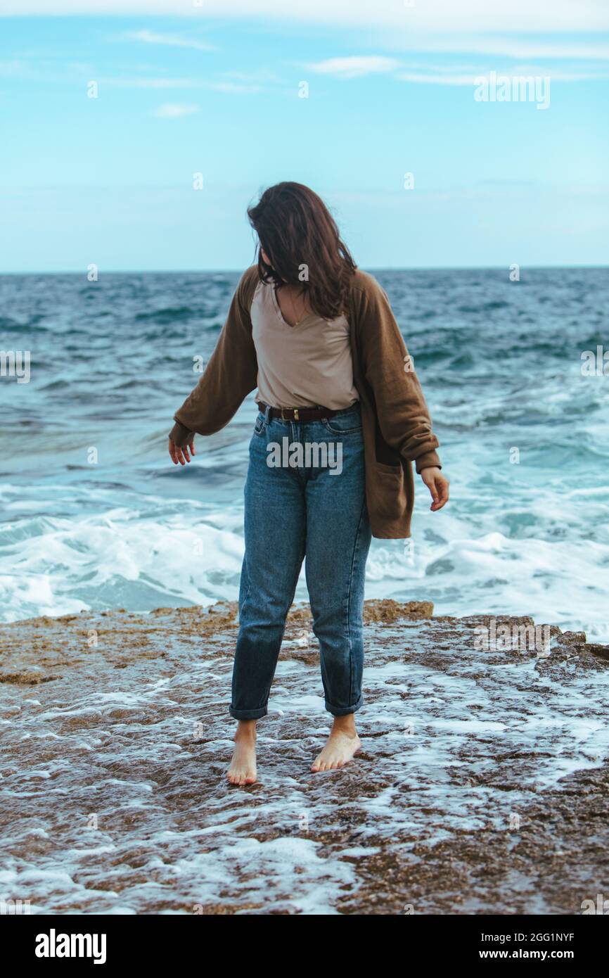 woman walking by rocky beach in wet jeans barefoot. summer sea vacation  Stock Photo - Alamy