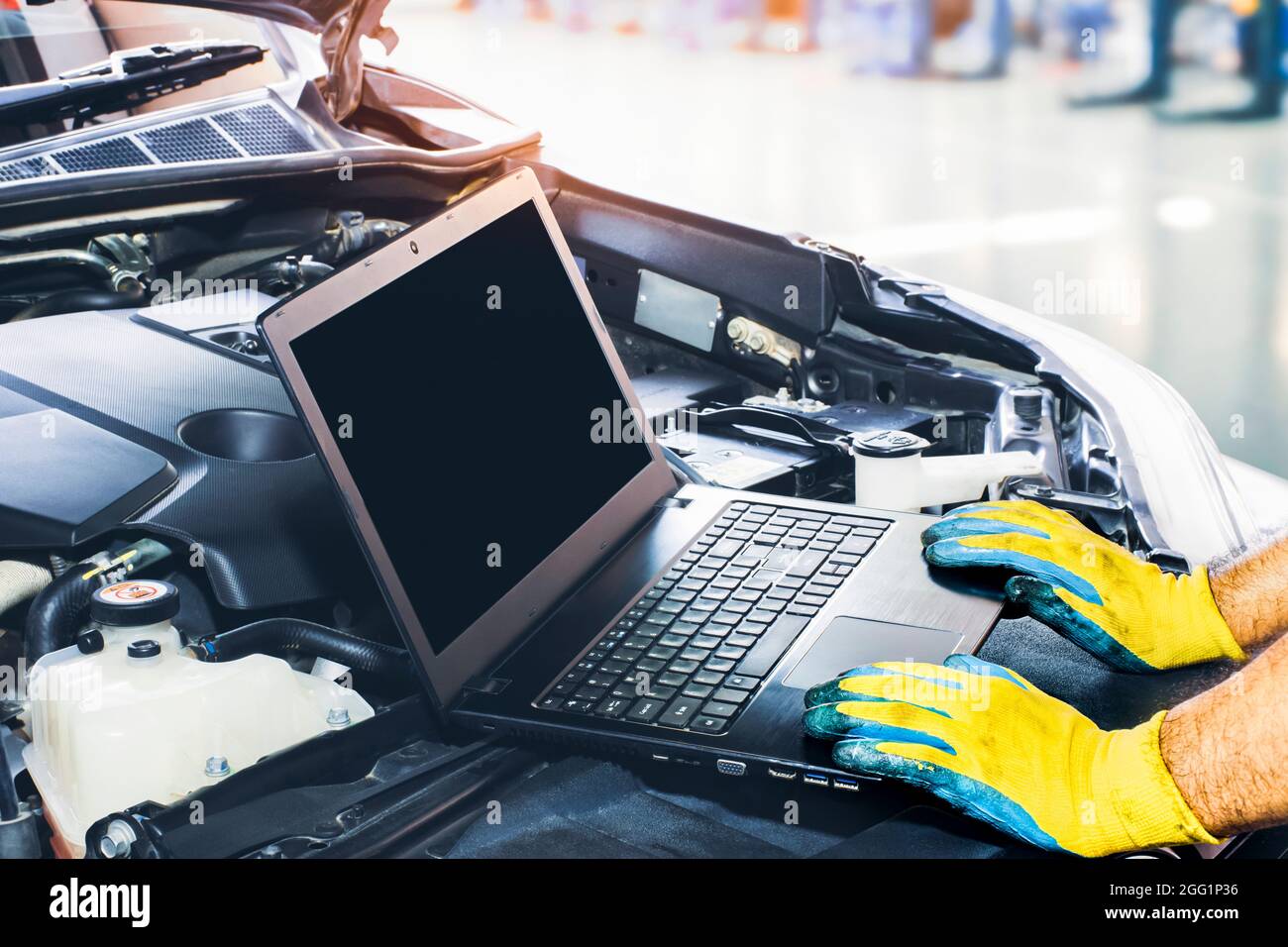 Technician tuning engine car with the computer laptop in repair garage