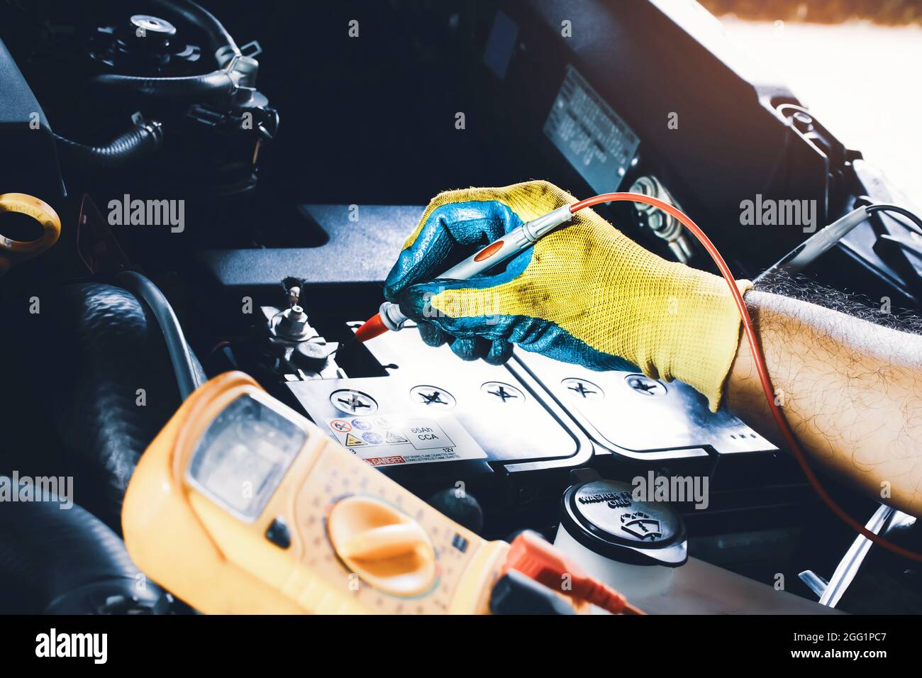 Technician to checking voltage stable of the car battery with digital multimeter probe Stock Photo