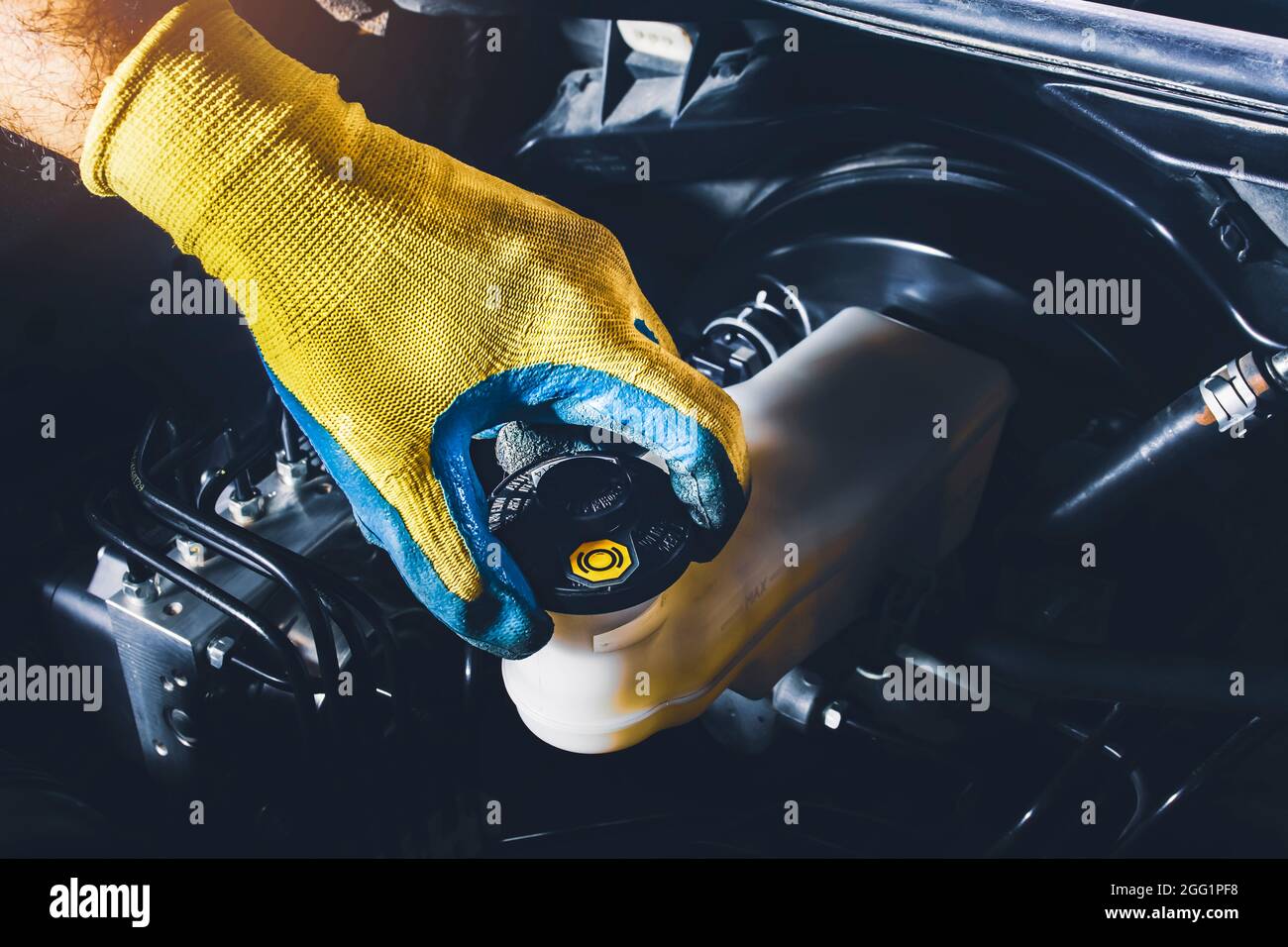 The mechanic is open or close the car's brake fluid reservoir cap to