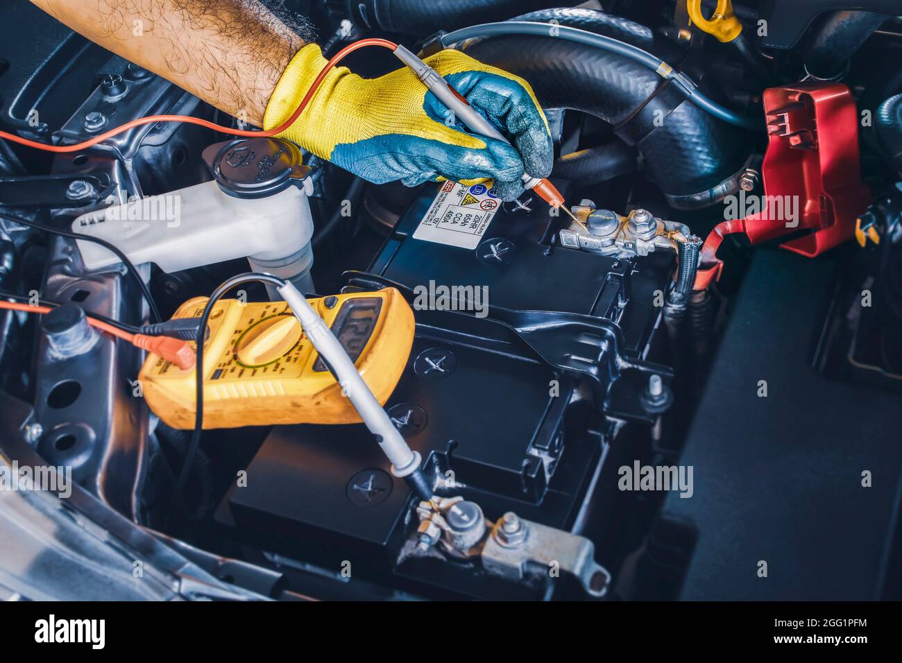 Technician checking DC voltage stable of the car battery with digital multimeter probe Stock Photo
