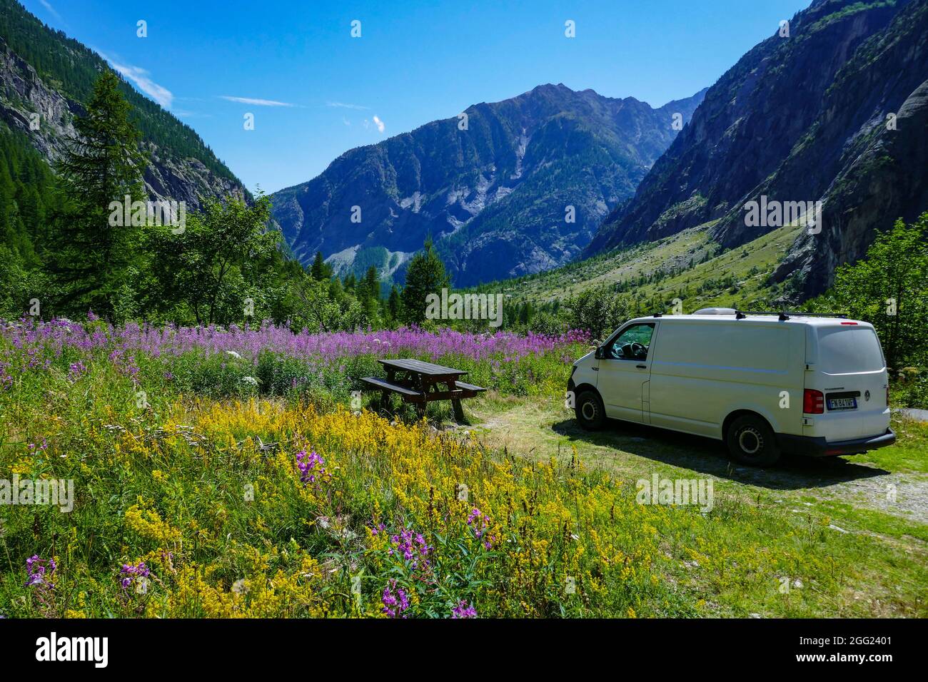 Campervan parked by picnic table Summer in the remote valley of Ailefroide, Briancon, Ecrins, France, French Alps Stock Photo