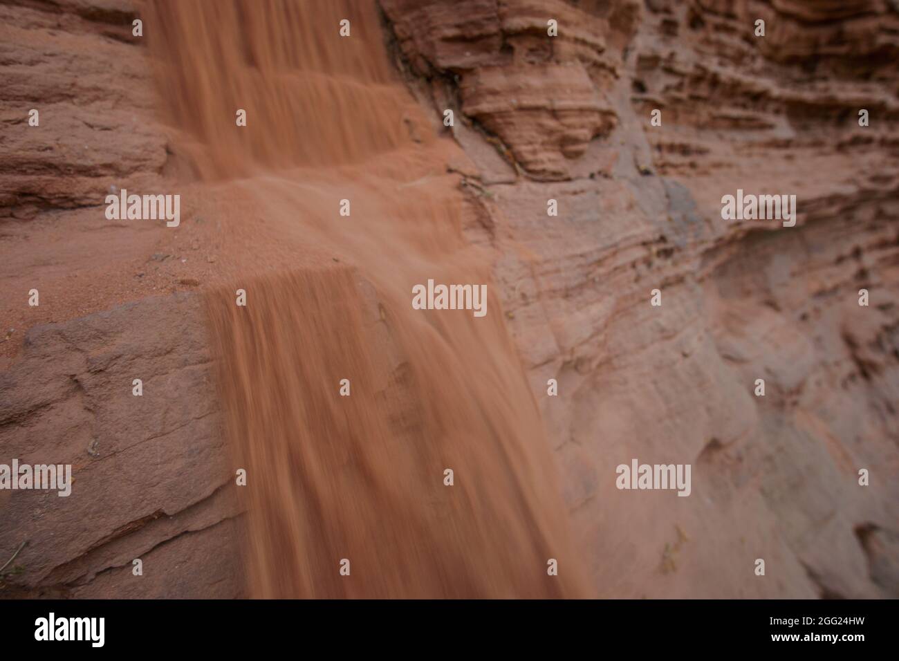 Close-up of red sandstone rock formation with sand falling down like a waterfall Stock Photo