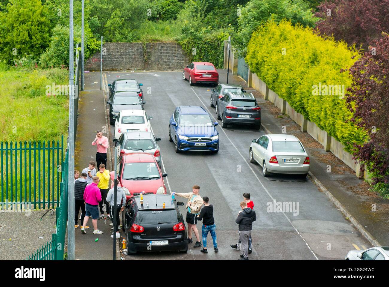 Young men hanging out at a backyard public car park or parking lot street drinking in Killarney, Ireland, Europe, EU Stock Photo