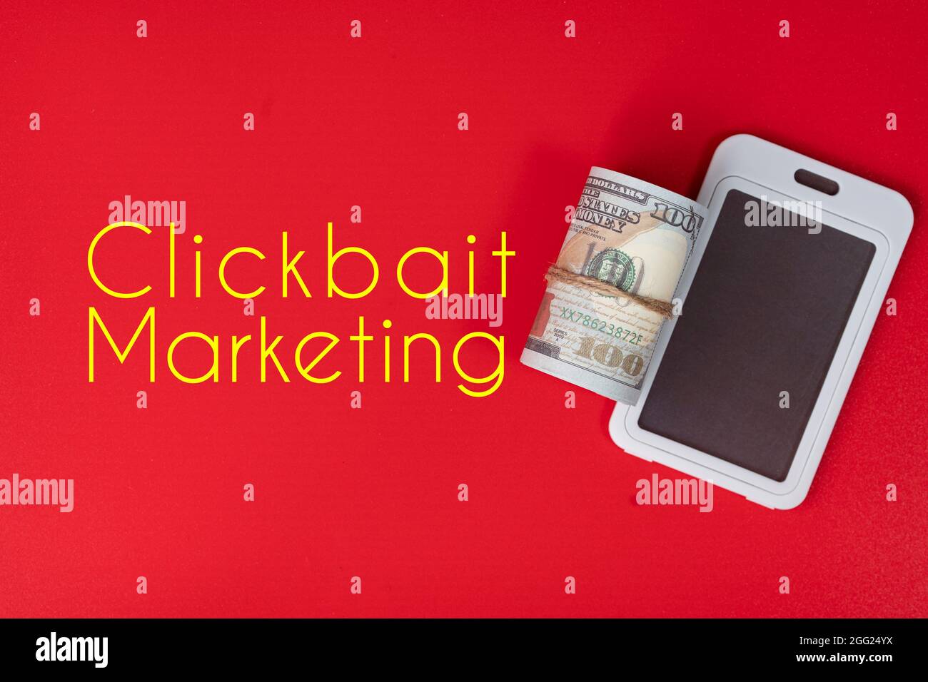 Mobile phone replica and a roll of fake money with text Clickbait Marketing. Clickbait is a method to entice user to click a post in the internet Stock Photo