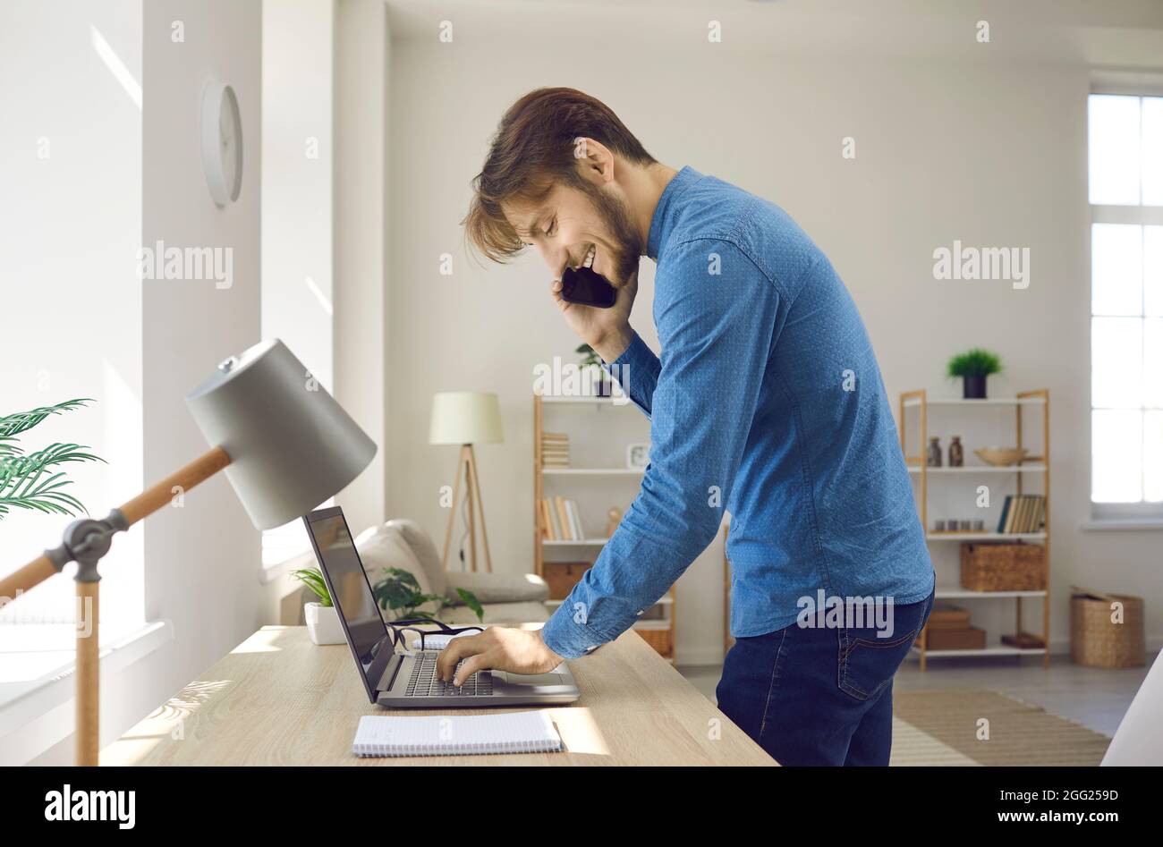 Friendly young businessman having business conversation on phone at work in office. Stock Photo