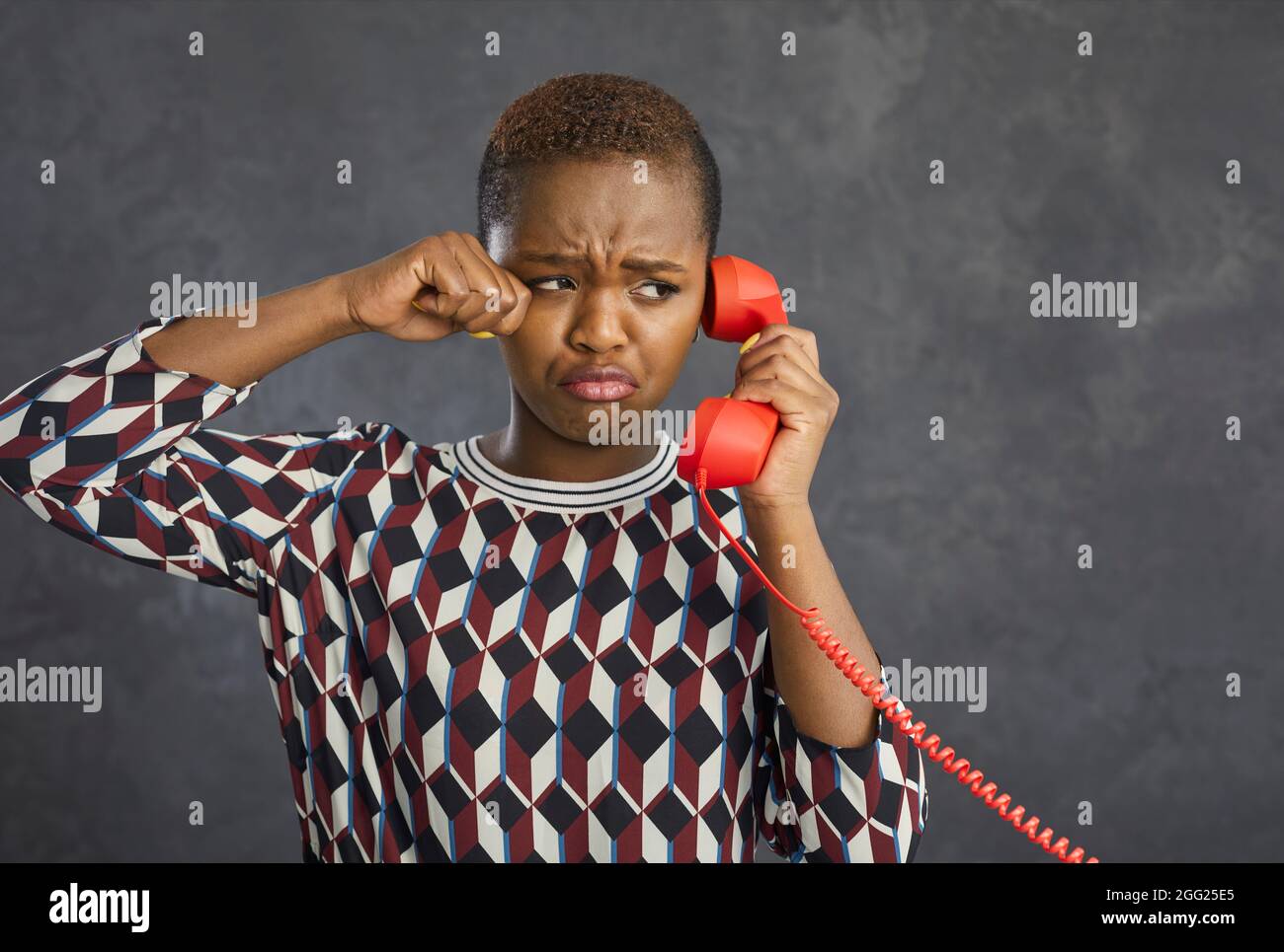 Portrait of unhappy capricious african american woman crying while talking on landline retro phone. Stock Photo