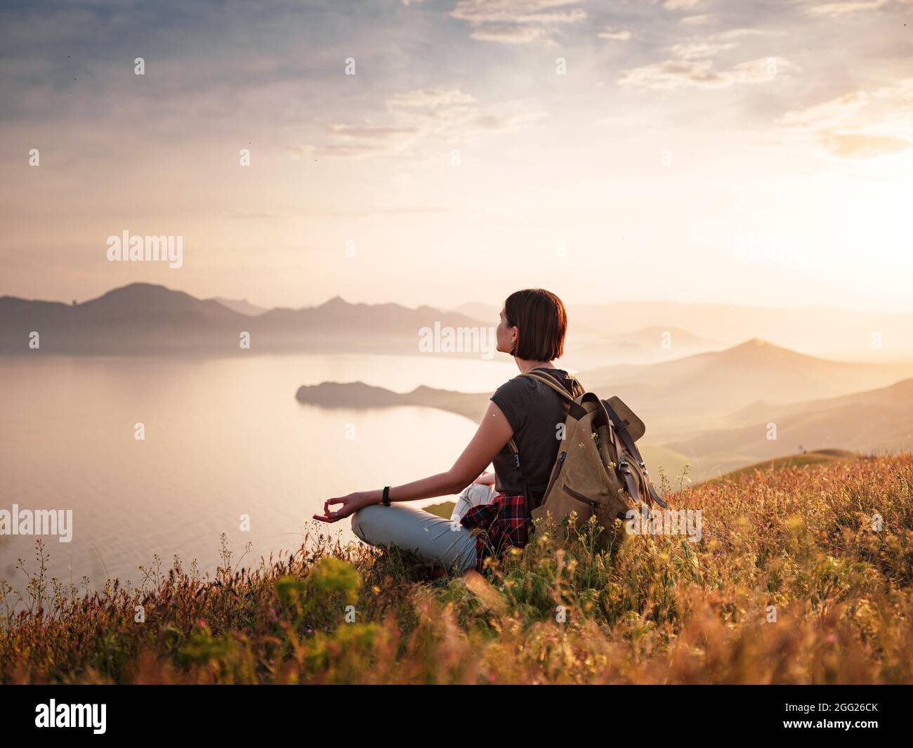 A young Asian woman with a backpack hiking in the summer climbing the ...