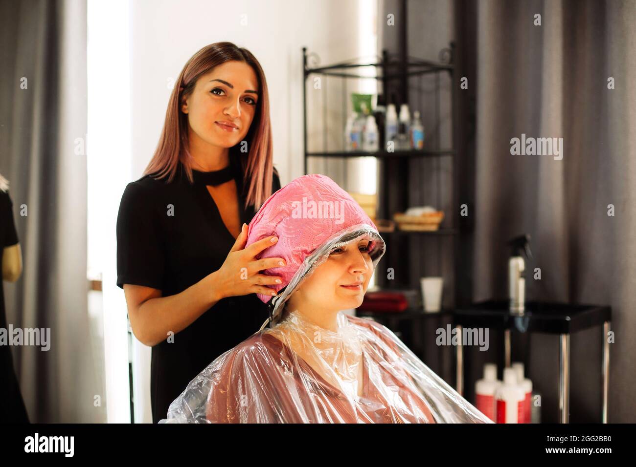 Happy woman with stylist making mask at salon. Competent female hairdresser deciding what to do