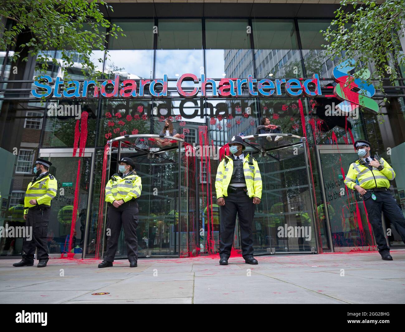 Extinction Rebellion protest Friday 27th August 2021, London UK. Protesters sit on top of doors of Standard Chartered bank, covered in fake blood during climate change protest Stock Photo