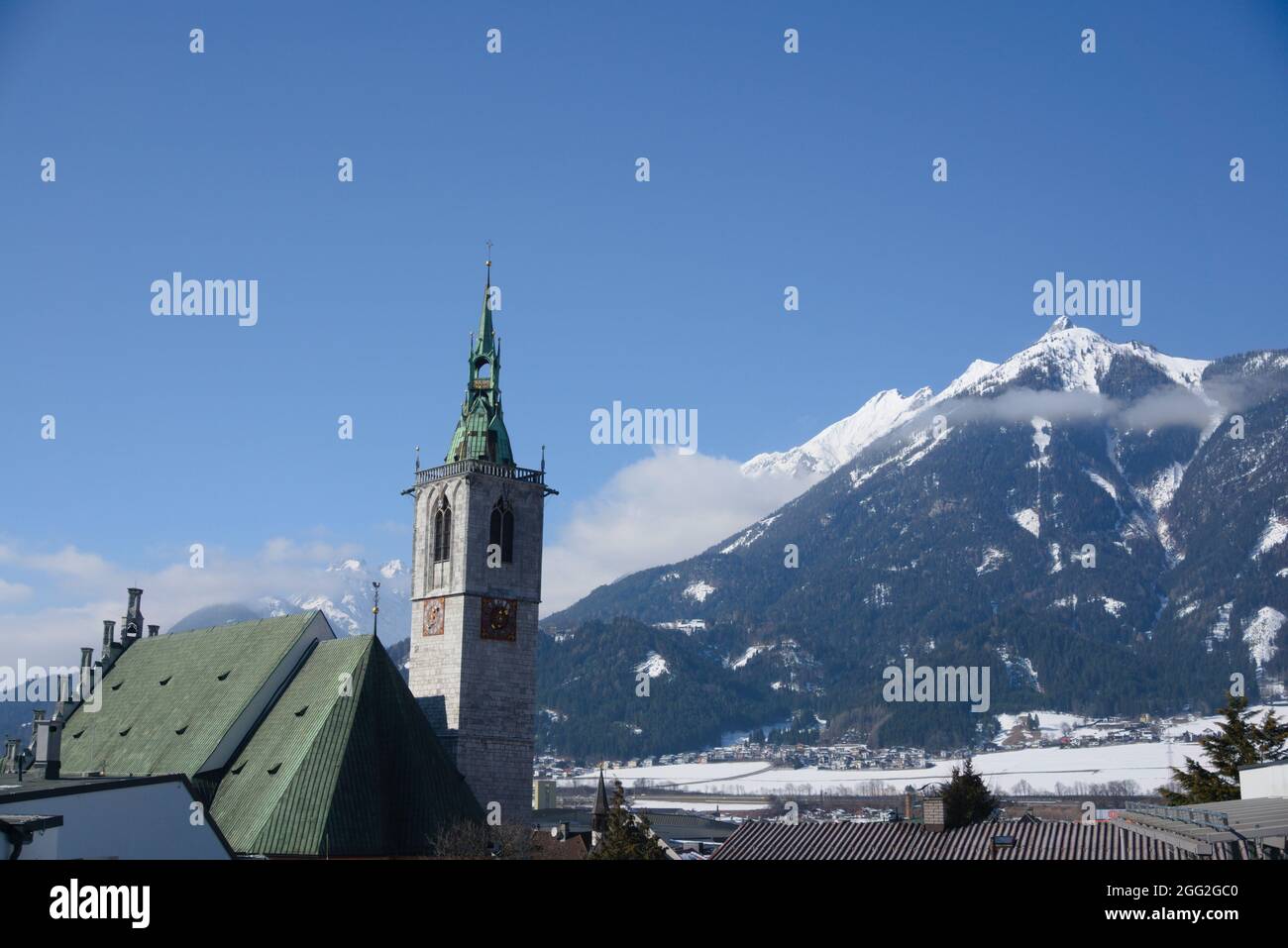 Church of schwaz in front of tyrolian mountains on a clear blue winter day Stock Photo