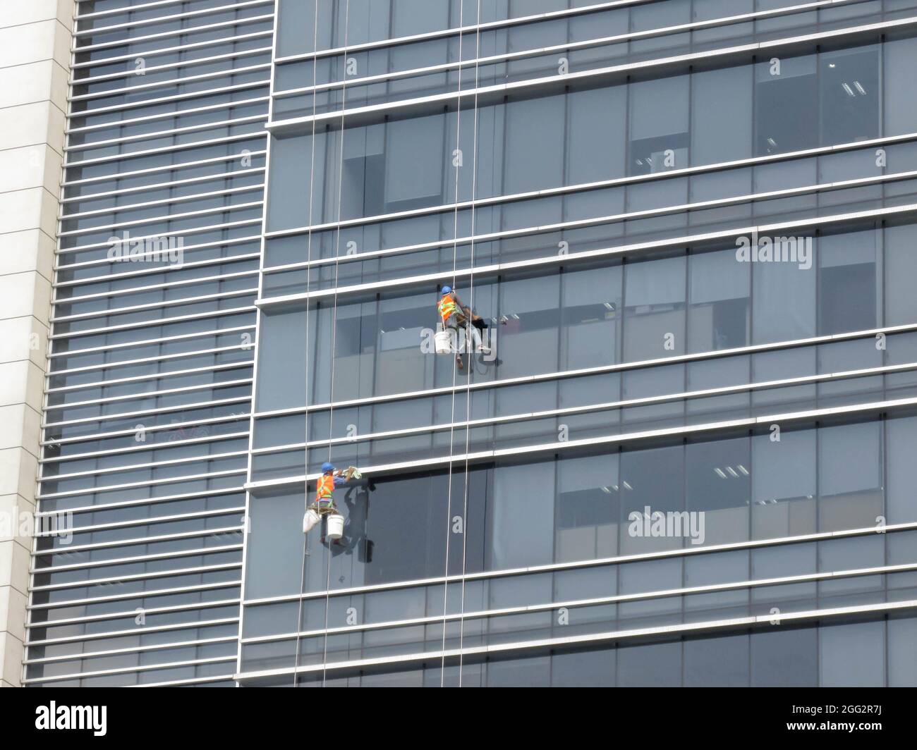 Ho Chi Minh, Vietnam - February 28, 2017: 2 workers are cleaning the outside glass of a high-rise building Stock Photo