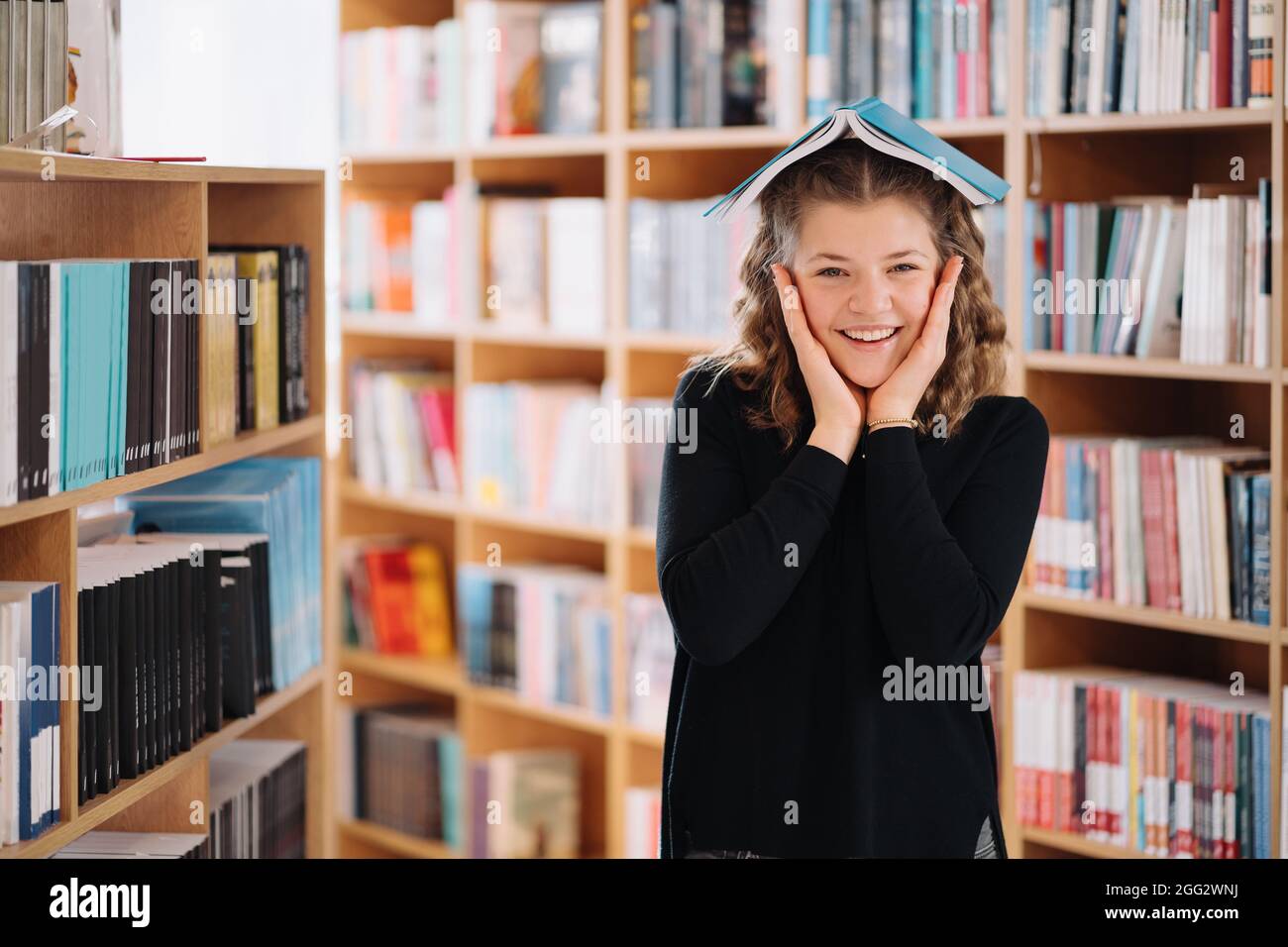 Portrait of funny smiling Caucasian teenager girl putting and holding a ...