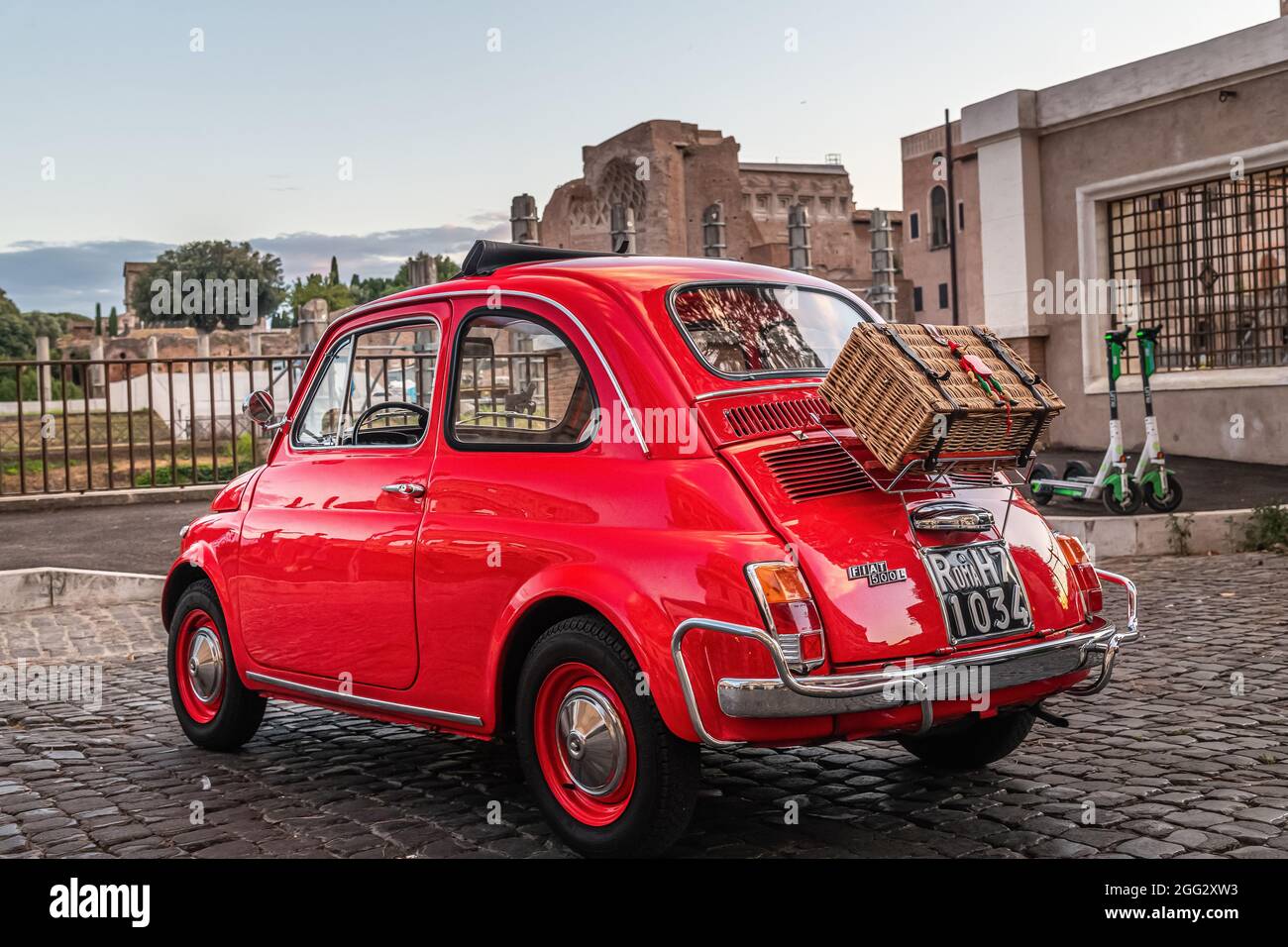 Little red old Fiat 500 in front of coliseum at sunset with picnic