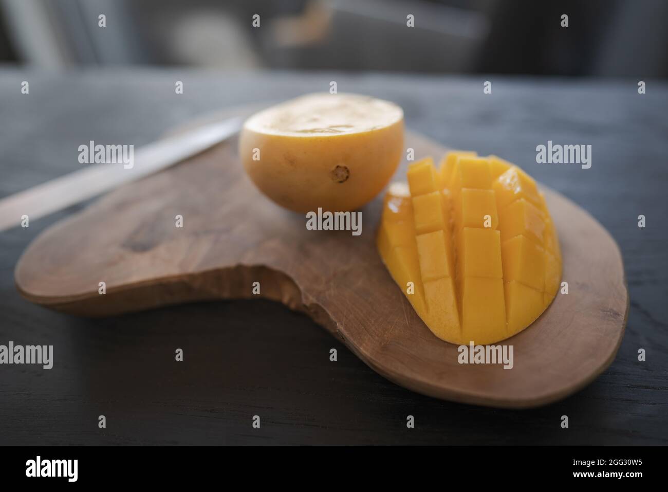 Cut in halves thai yellow mango on olive wood board, shallow focus Stock Photo Alamy