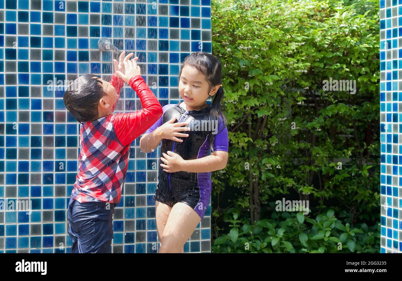Asian kid wash salt water out of his face. The older sister shower her