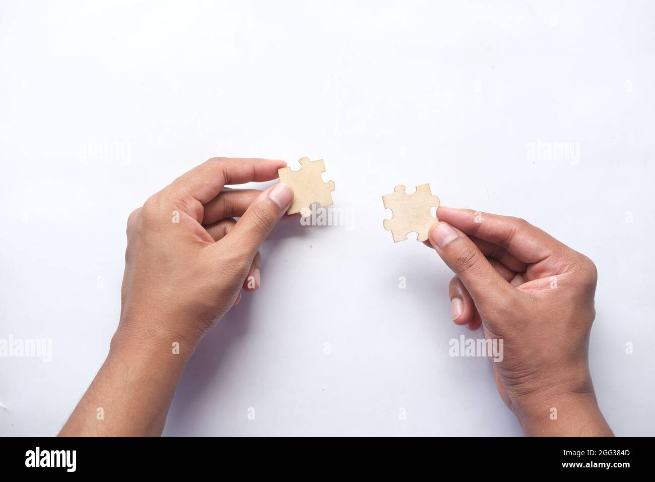 man hand hold connecting puzzle on table Stock Photo