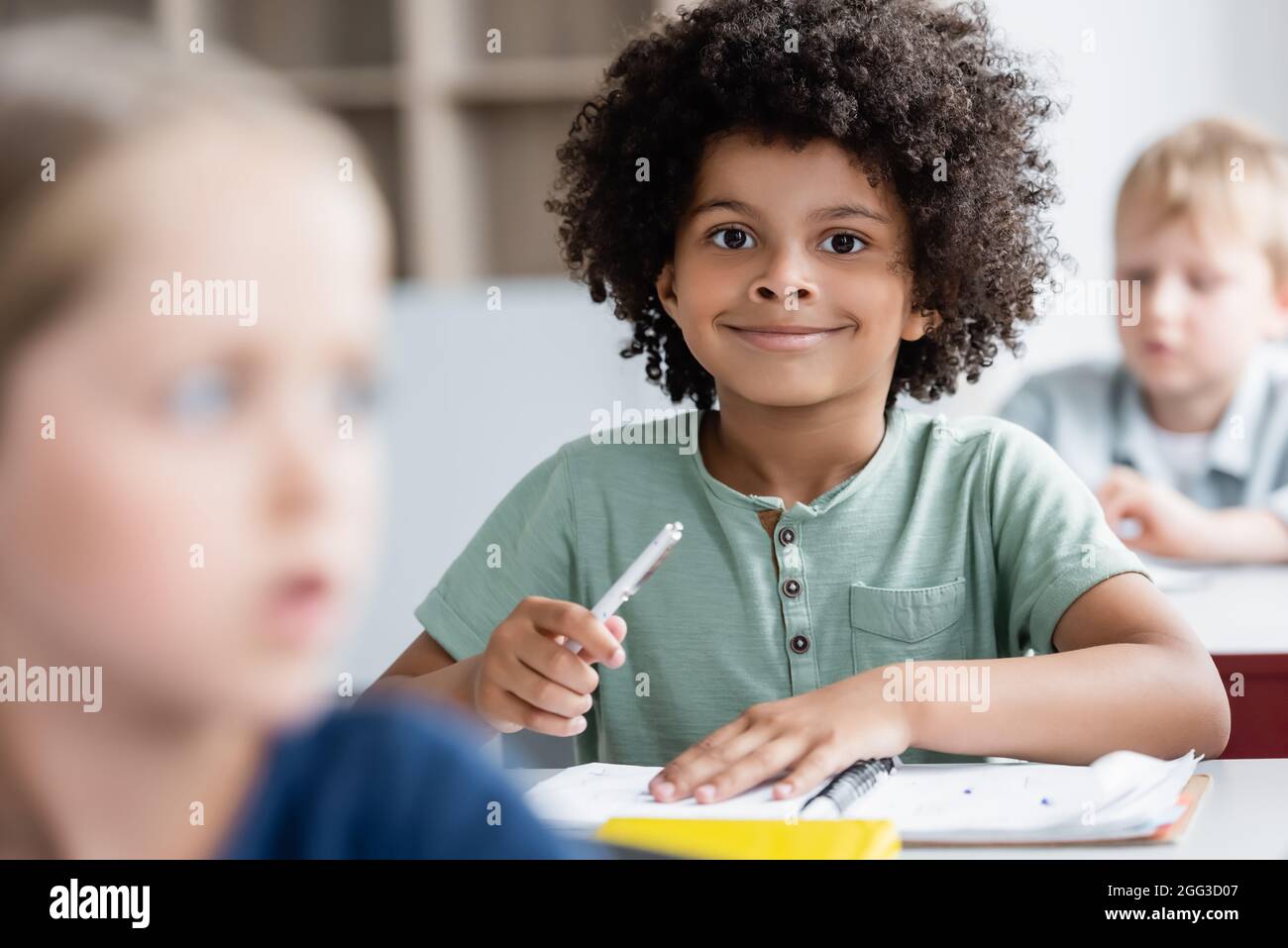 african american kid smiling at camera near blurred classmates Stock ...
