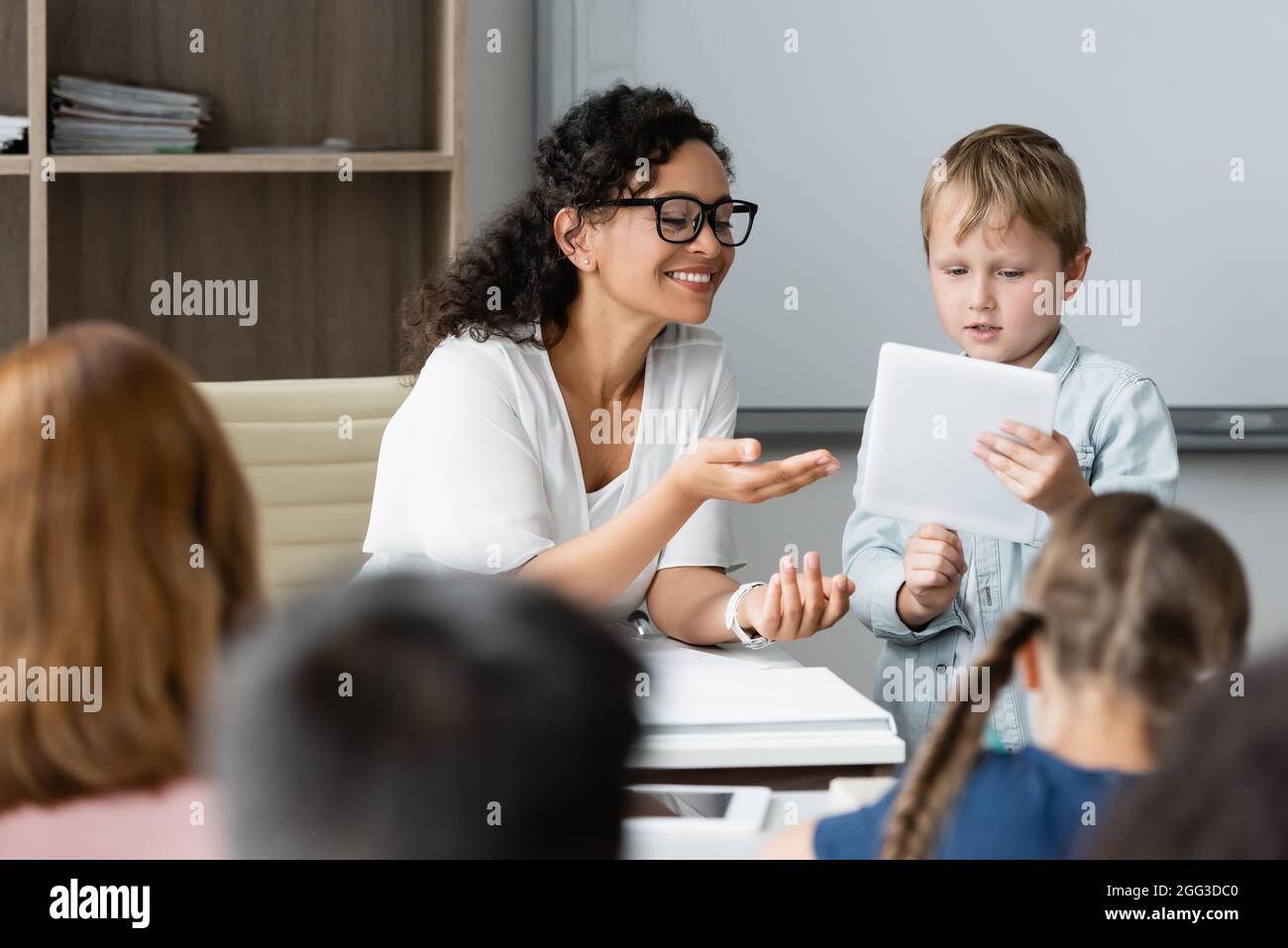 smiling african american teacher pointing at digital tablet in hands of ...