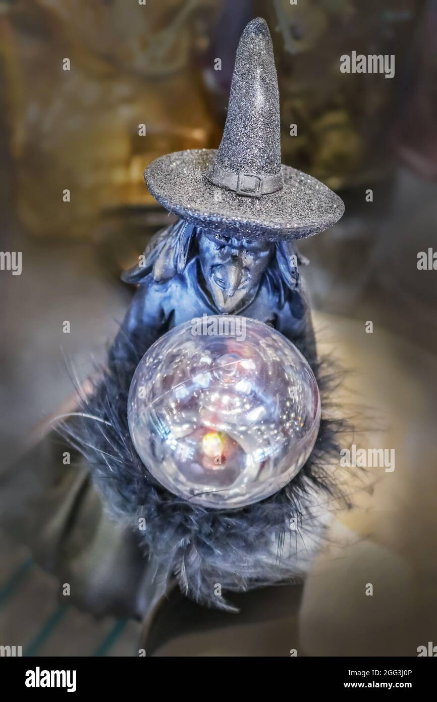 Wicked witch Halloween decoration with crystal ball and sparkly hat against bokeh background Stock Photo