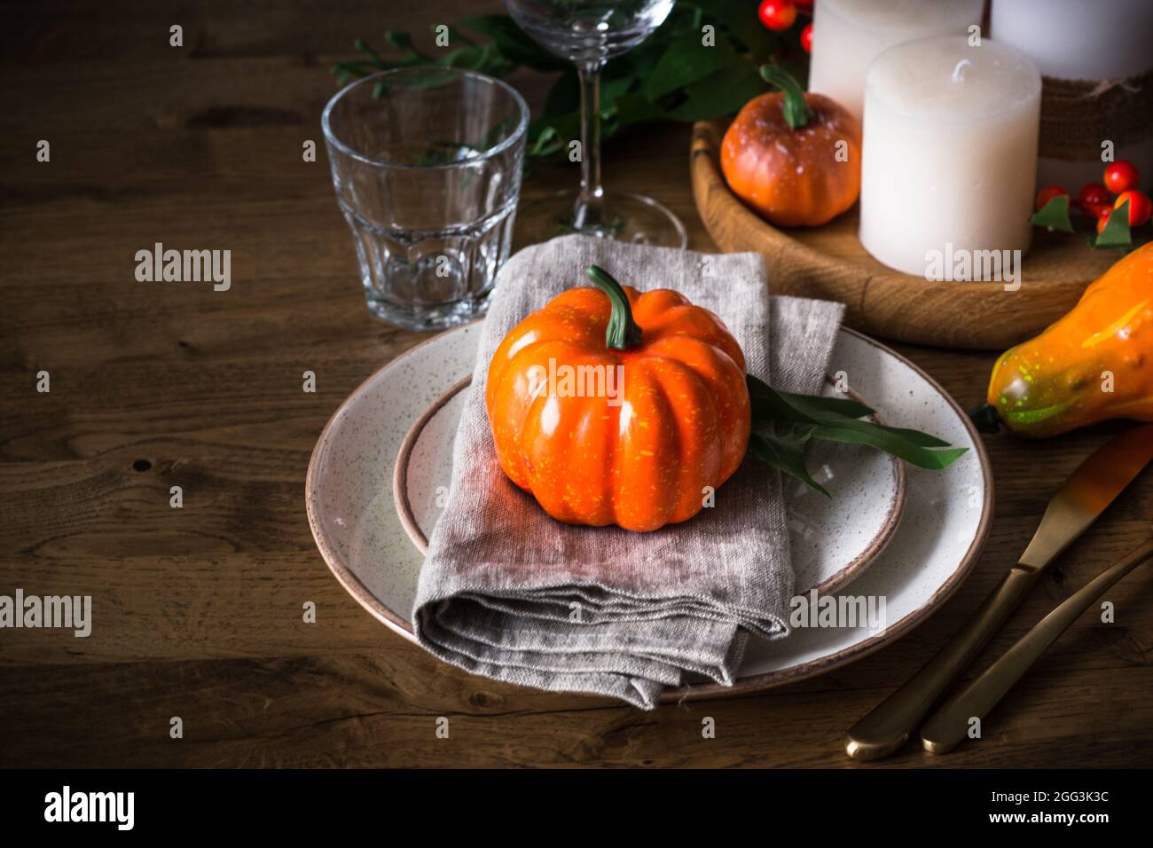 Autumn table setting with plate, pumpkin and candles. Stock Photo