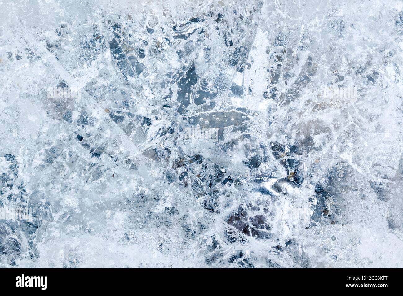 Ice encapsulating small stones and air bubbles, creating a highly textured effect Stock Photo