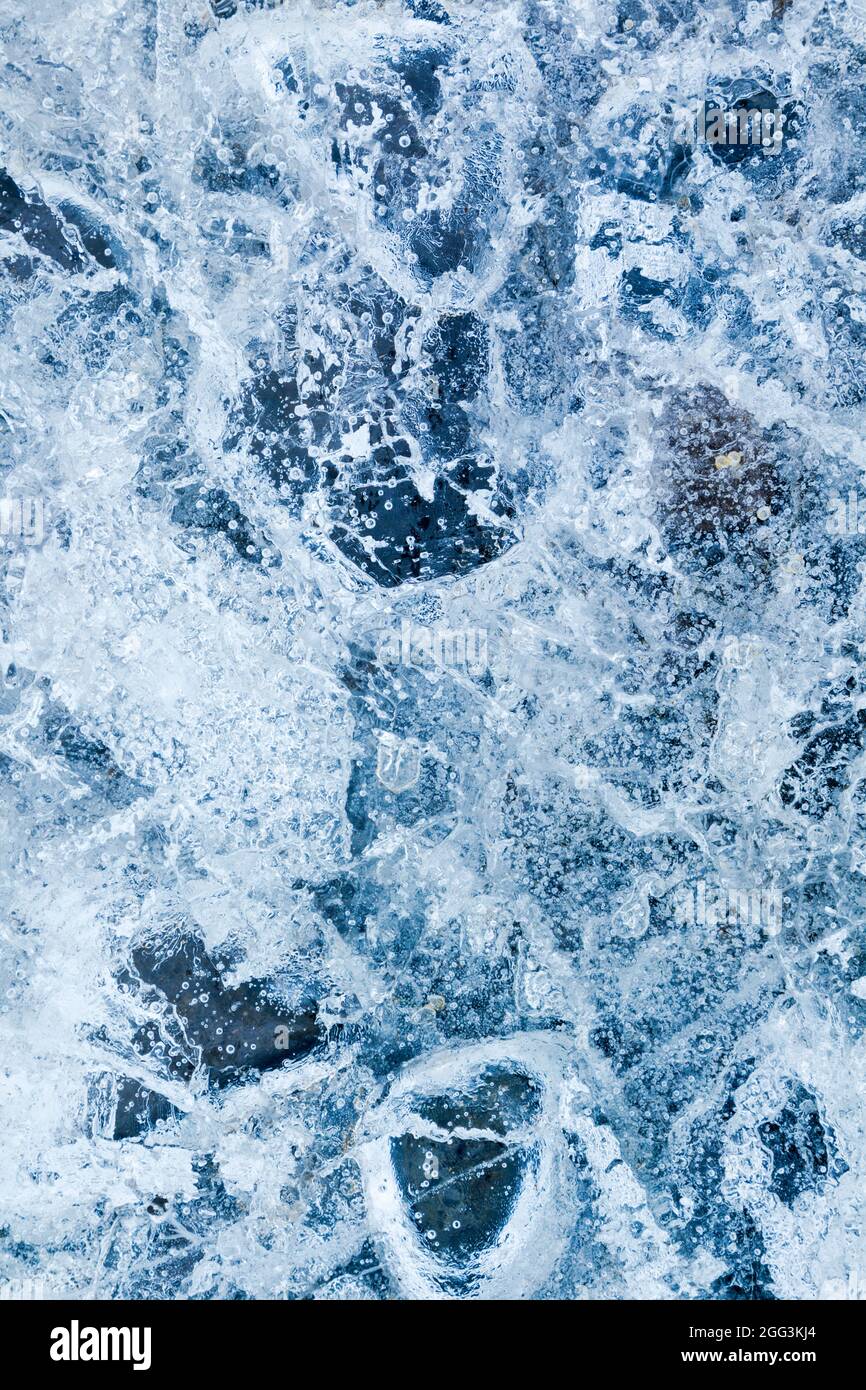 Ice encapsulating small stones and air bubbles, creating a highly textured effect Stock Photo