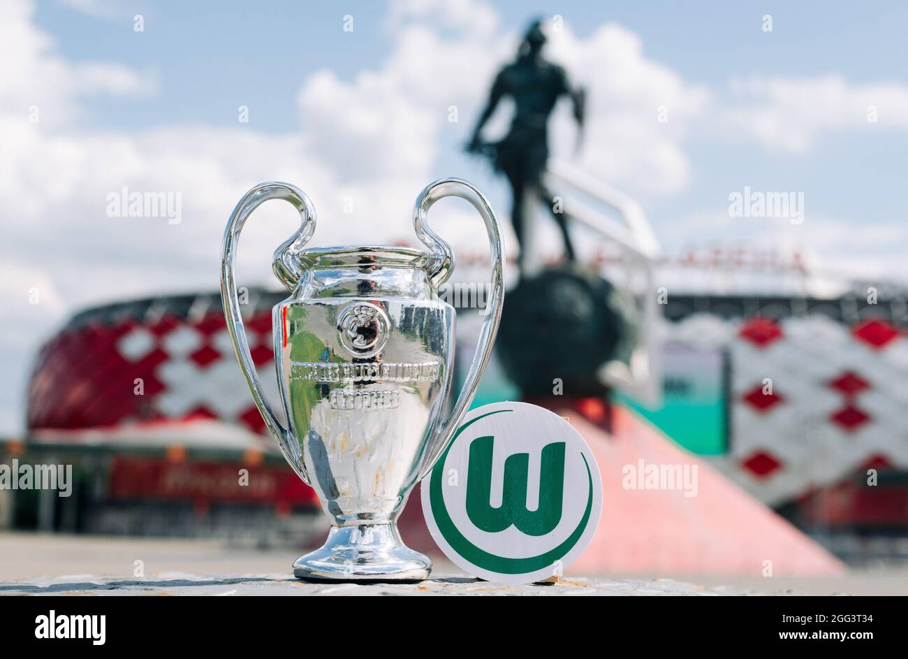 June 14, 2021 Wolfsburg, Germany. The emblem of the football club VfL Wolfsburg and the UEFA Champions League Cup against the backdrop of a modern sta Stock Photo