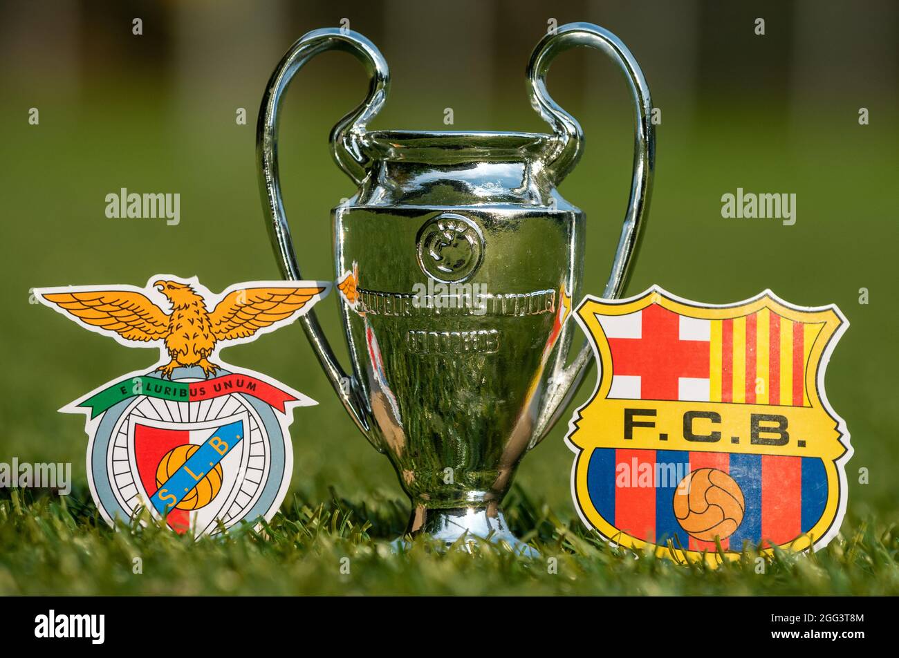 August 27, 2021 Lisbon, Portugal. The emblems of football clubs S.L. Benfica and FC Barcelona and the UEFA Champions League Cup on the green lawn of t Stock Photo