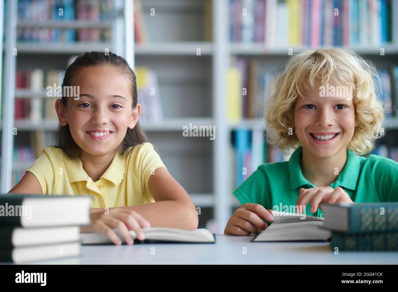 Two Schoolchildren Posing For The Camera At The Library Desk Stock 