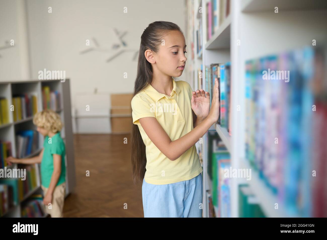Two schoolchildren focused on choosing different books Stock Photo