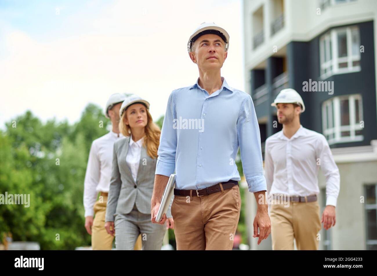 Four colleagues in hardhats inspecting the construction site Stock Photo