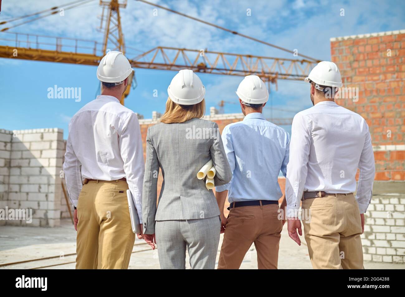 Four people examining in safety helmets a new construction object Stock Photo