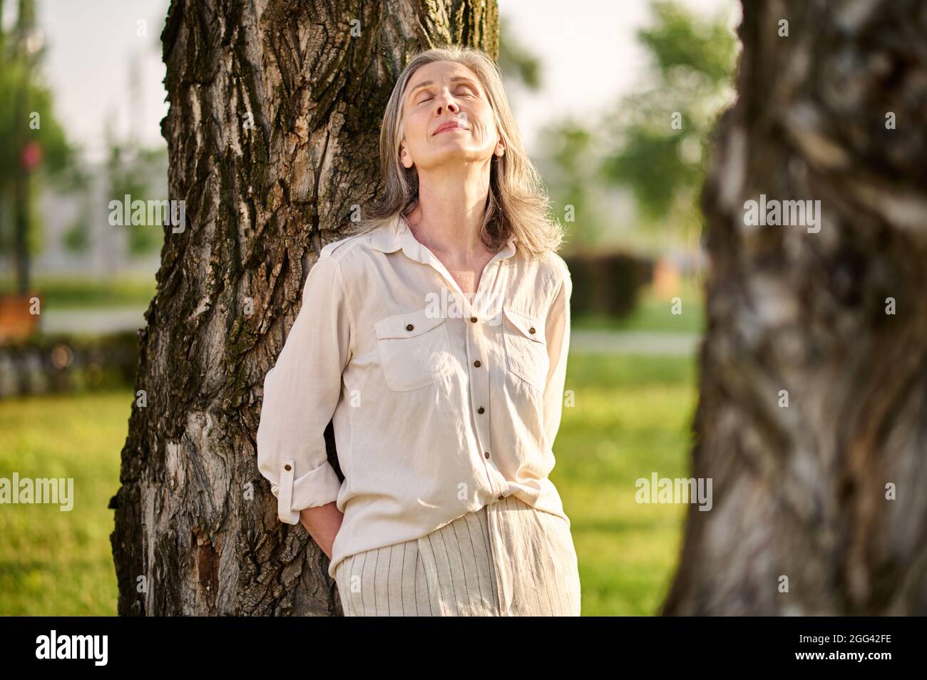 Relaxed woman with closed eyes near tree Stock Photo - Alamy