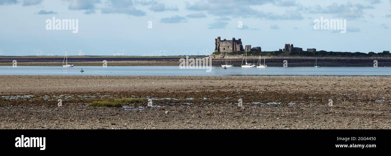 Yachts and Piel Castle on Piel Island viewed at low tide from Roa Island on the Furness Peninsula Stock Photo