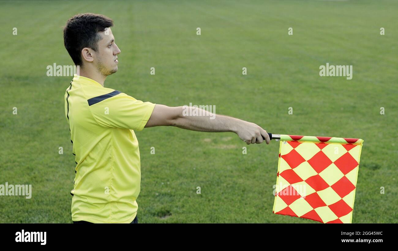 Assistant referee moving along the sideline during a soccer match. Linesman hand with flag