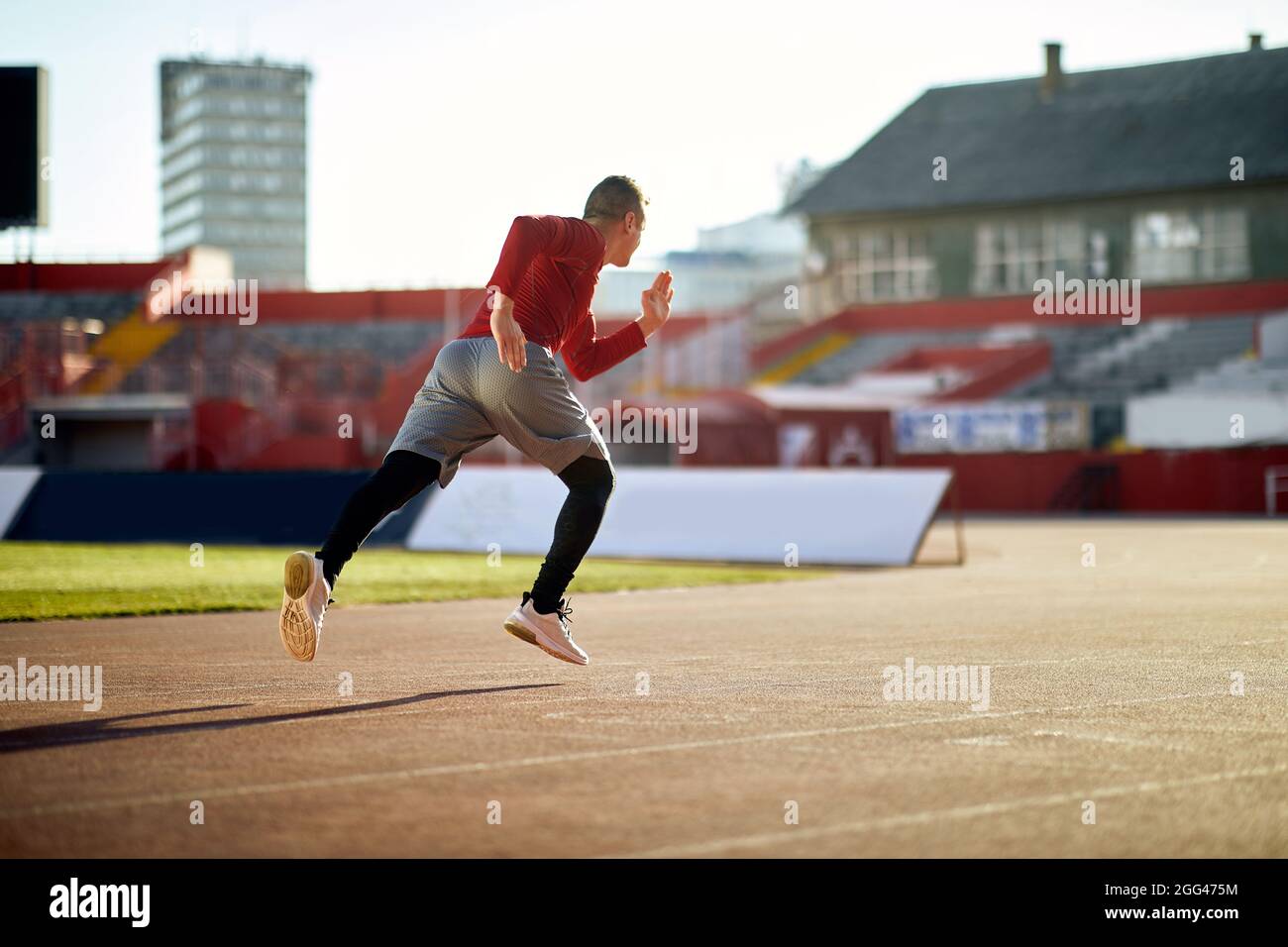 Athletic young man sprinter running on stadium. Stock Photo