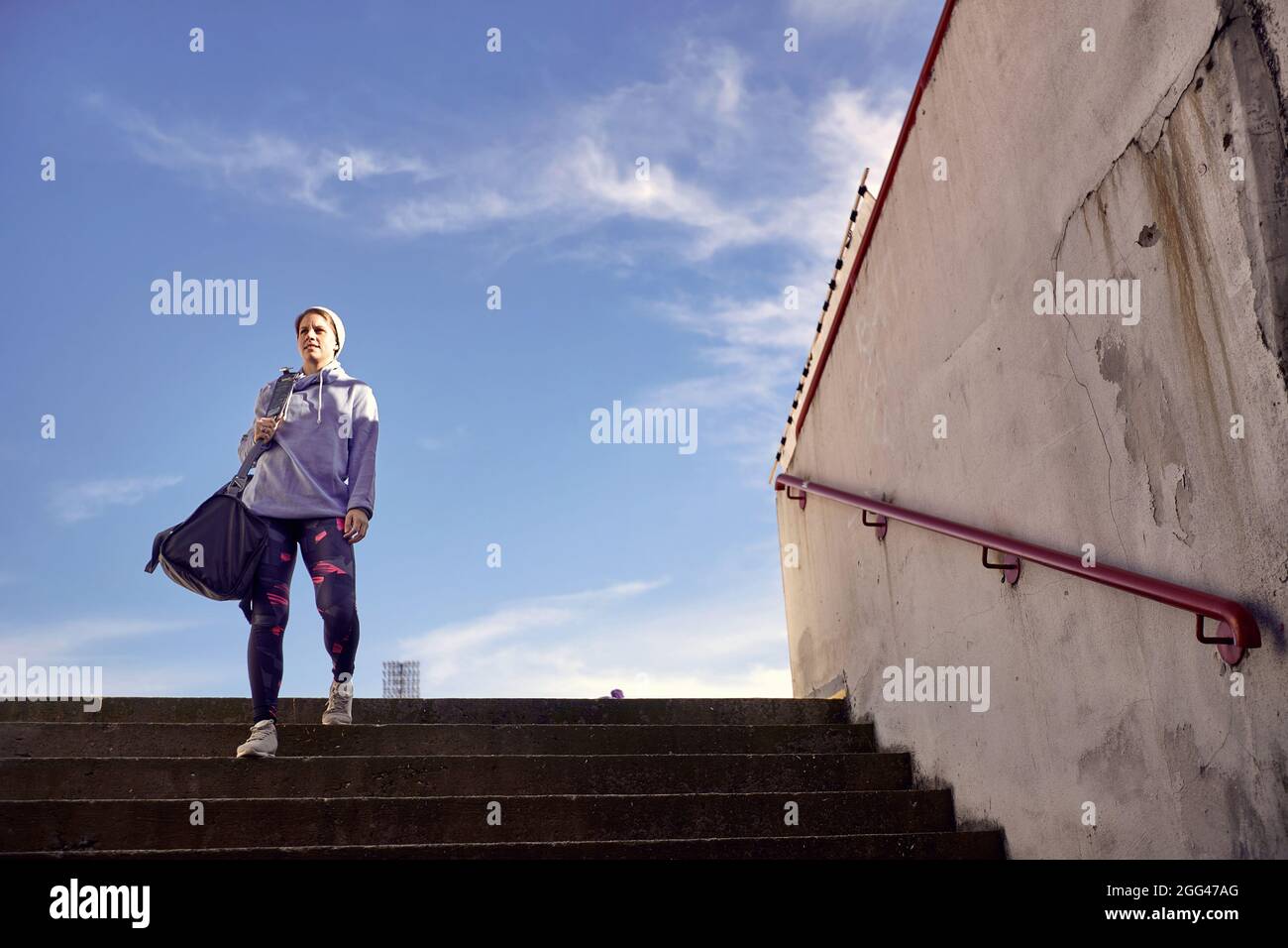Activity girl runner holds sport bag, training on stadium Stock Photo