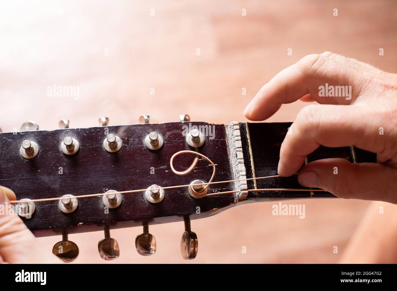 Repair of an old guitar. The man pulls the strings on the fretboard