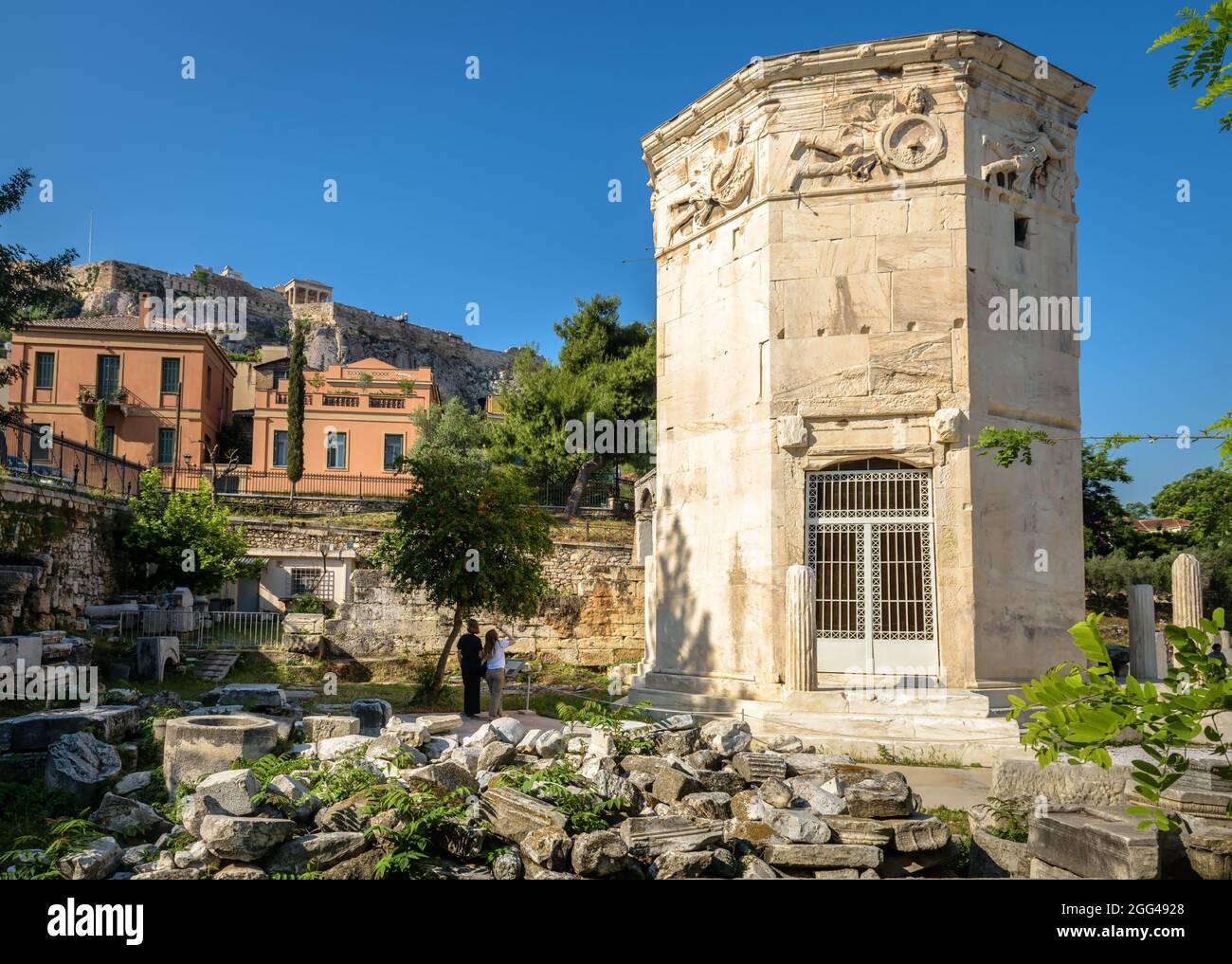 Tower of Winds or Aerides in Roman Agora, Acropolis in distance, Athens, Greece. It is tourist attraction of Athens. View of Ancient Greek ruins in At Stock Photo