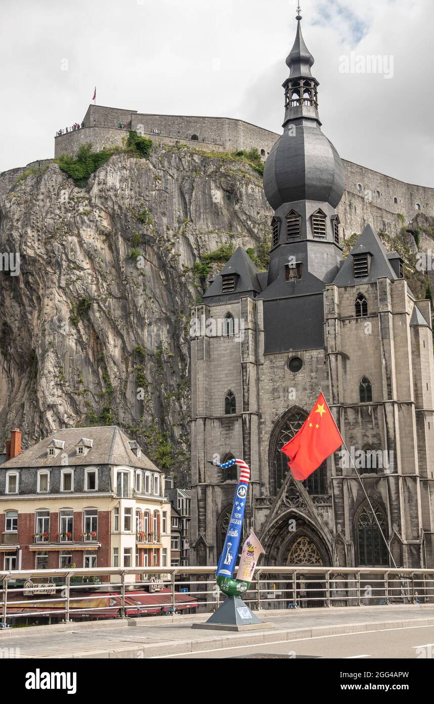 Dinant, Wallonia, Belgium - August 8, 2021: Citadel Fort. Chinese communist flag, American flag themed saxophone statue in front of Collégiale Notre D Stock Photo
