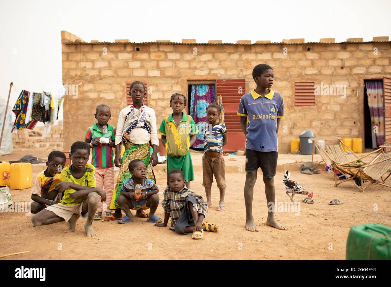 Sons, daughters, nieces and nephews from and extended  family huddle together in a compound where more than 30 of their family members stay in Nouna, Burkina Faso. The extended family has been displaced due to violence and insecurity and now faces hunger and food shortages. Stock Photo