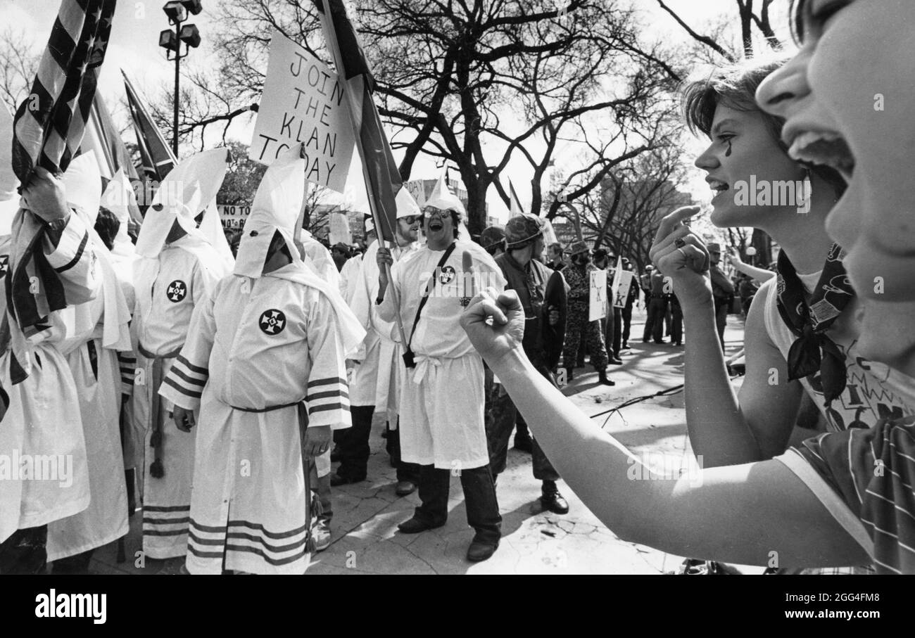 Austin Texas USA, Feb. 26, 1983: Members of the Southern hate group Ku Klux Klan (KKK), clad in white robes and hoods, rally at the Texas Capitol as onlookers protest the Klan's racist ideals. ©Bob Daemmrich Stock Photo