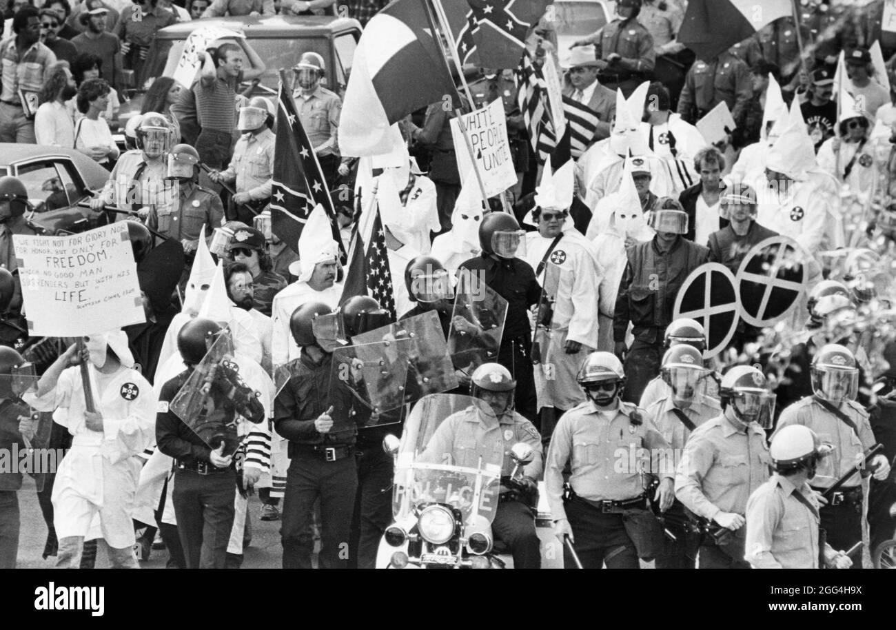 Austin, Texas USA, circa 1983: Small group of Ku Klux Klan members, flanked by police, parade through downtown Austin, where they are met by a hostile anti-KKK crowd. ©Bob Daemmrich Stock Photo