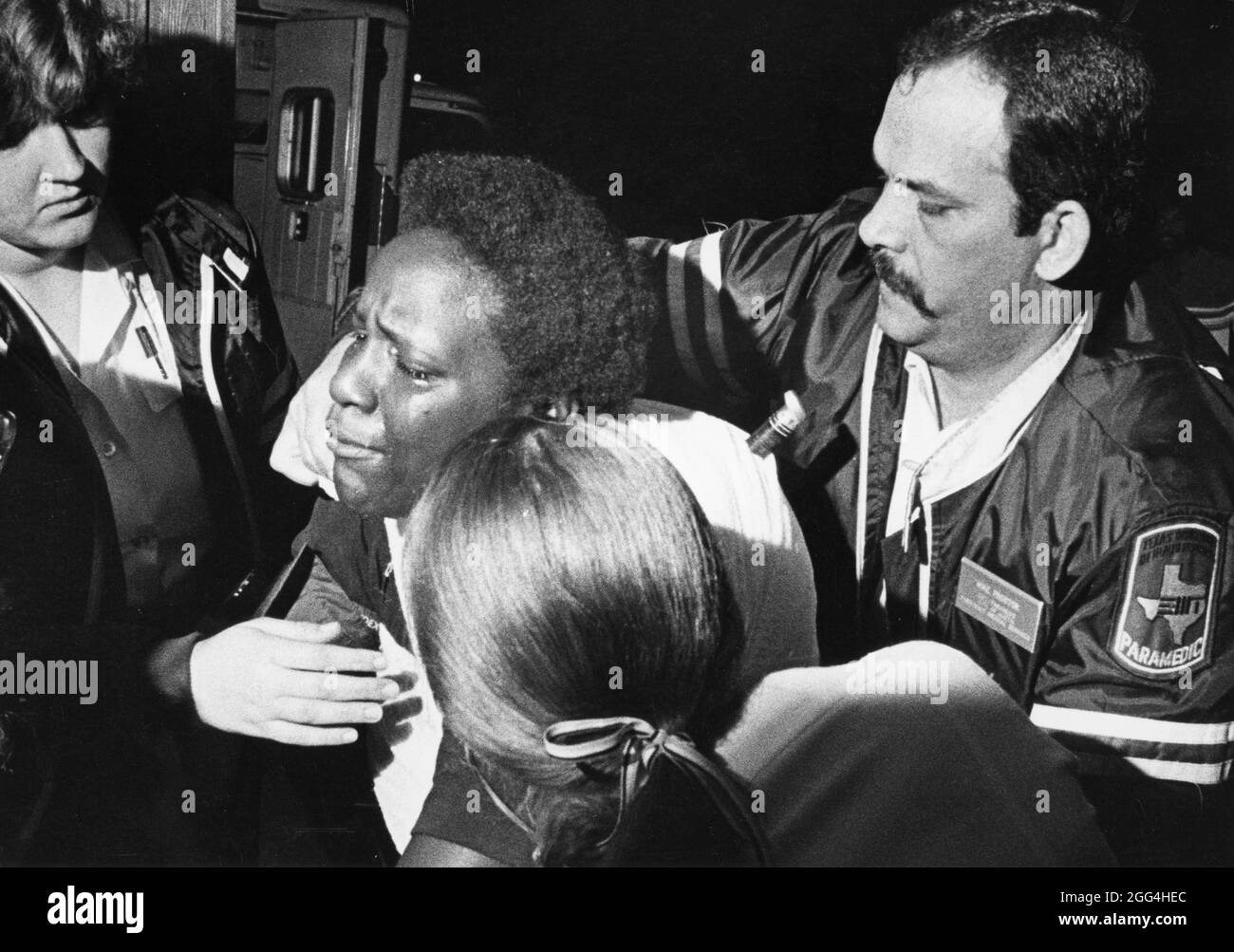 Austin, Texas USA, circa 1986: Emergency Medical Services technicians aid stabbing victim and walk her to ambulance. Note that knife is still embedded in victim' back. ©Bob Daemmrich Stock Photo