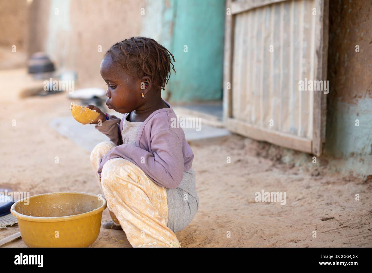 A young girl eats a bowl of millet porridge for breakfast outside her ...