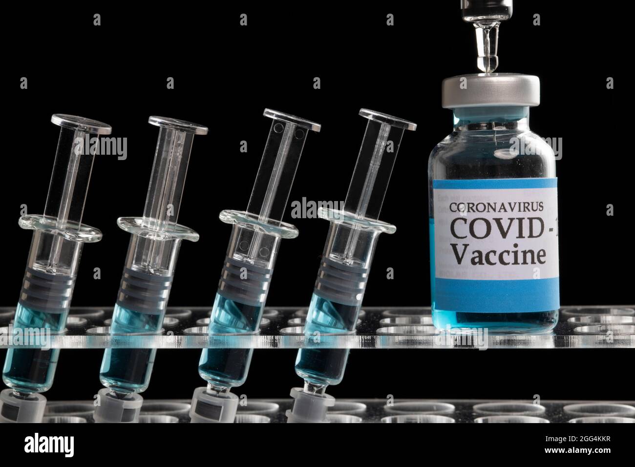 Glass syringes and glass vial filled with blue liquid on a clear ...