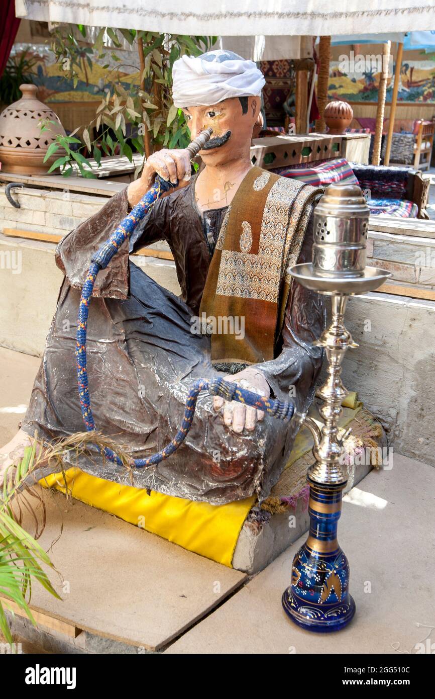 A seated manikin showing a man smoking from an Egyptian Hookah at the entrance to a restaurant at Luxor in central Egypt. Stock Photo