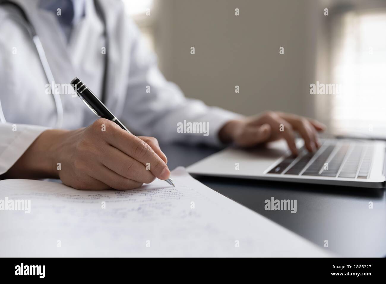 Close up young female gp doctor handwriting notes. Stock Photo